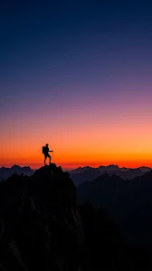 Silhouette of a Lone Hiker on a Peak Against Fiery Red Dawn Sky