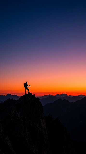 Silhouette of a Lone Hiker on a Peak Against Fiery Red Dawn Sky - Free mobile Wallpaper