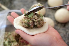 Cán mỏng bột bánh bao rồi cho phần nhân bánh vào nặn bánh bao thôi nào! Cứ nặn thành chiếc bánh tròn như bình thường nghen. Có thể lấy đế giấy để lót cho bánh bao để chống dính khi hấp.