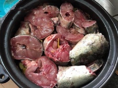 Cho 1 thìa dầu ăn dưới đáy nồi rồi xếp lần lượt thịt ba chỉ, riềng, cá, ớt quả, chuối xanh, sả lên trên. Nêm thêm nước mắm, bột ngọt, hạt tiêu, nước hàng vào nồi. Cho nước dừa xiêm ngập mặt cá.