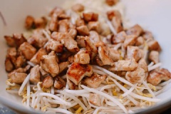 Chuẩn bị 1 chảo dầu lớn. Cho thịt gà đã nguội cùng hành tây thái hạt lựu và giá đỗ vào bát trộn. Thêm trứng, dầu mè và bột bắp. Nhớ là không được thêm bất cứ gia vị nào vào hỗn hợp này vì khi chiên trứng của bạn sẽ không kết lại với nhau. Sau đó trộn đều tất cả lại với nhau.