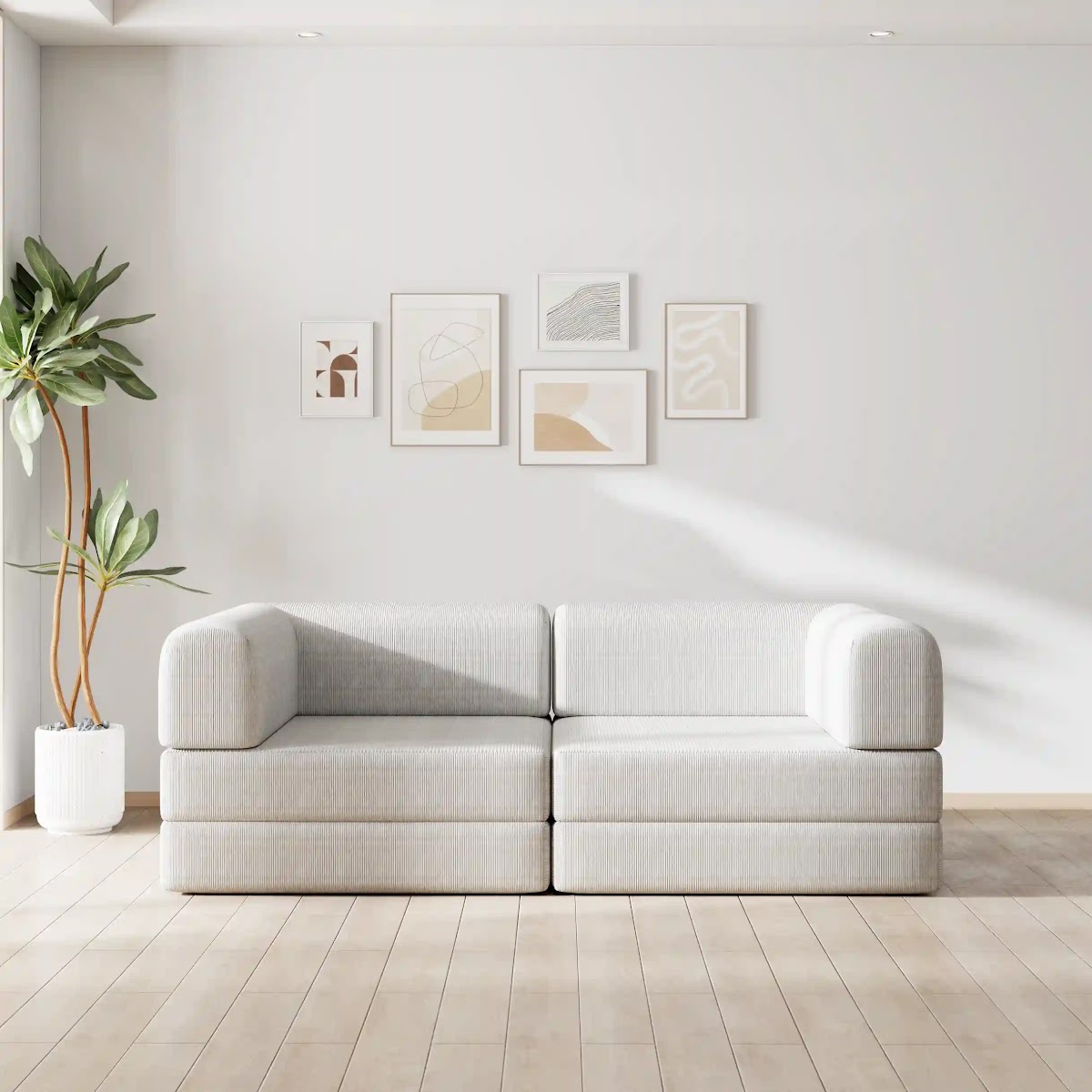 Woman relaxing under a throw on a grey modular sofa unfolded into a flat guest bed by a window