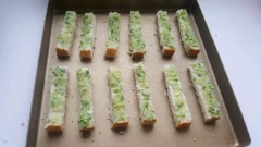 Phết đều hỗn hợp sốt bơ tỏi vừa pha lên trên các dải bánh mì sandwich. Cho khay nướng vào lò ở 180 độ C, nướng bánh mì bơ tỏi khoảng 8-10 phút là được.