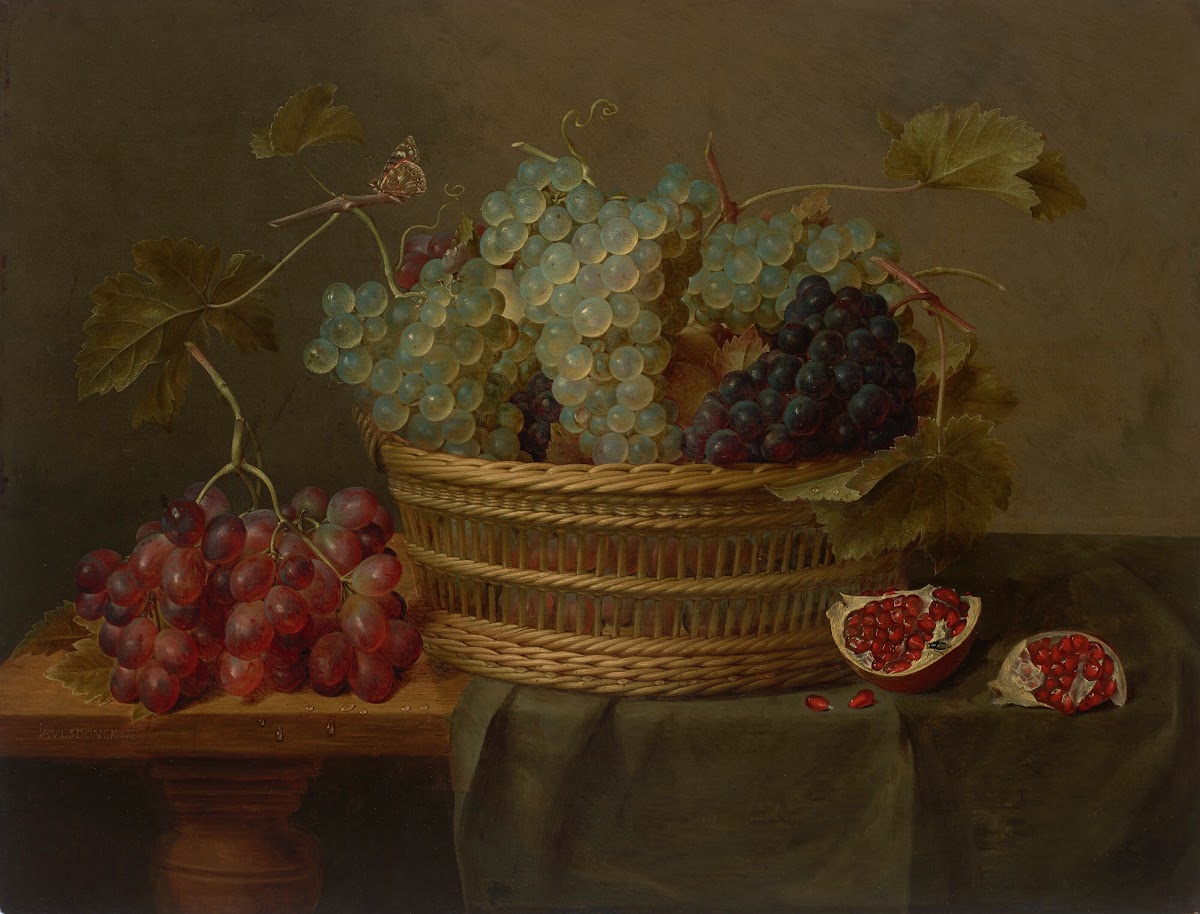 A basket of grapes and a pomegranate on a table