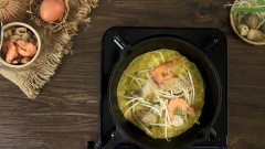 Đun nóng chảo gang, cho 1 muỗng canh dầu ăn vào phết đều chảo. Đổ 1 vá bột tráng đều chảo, thêm nhân tôm thịt, nấm rơm và giá đỗ. Đậy nắp trong 1 phút. Sau đó, đánh tan trứng vịt đổ vào rìa bánh. Tiếp tục, đổ thêm 2 muỗng canh dầu ăn vào mép bánh để bánh được giòn ngon. Chiên bánh thêm 2 phút nữa thì lấy bánh ra hoặc gập bánh lại.