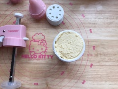 Cho hỗn hợp bột bánh quy bơ vào khuôn bánh hình hoa cúc, nén hơi chặt rồi úp ngược khuôn bánh ra khay nướng, gõ nhẹ để bánh rót xuống khay. Làm tương tự cho đến hết nguyên liệu.
