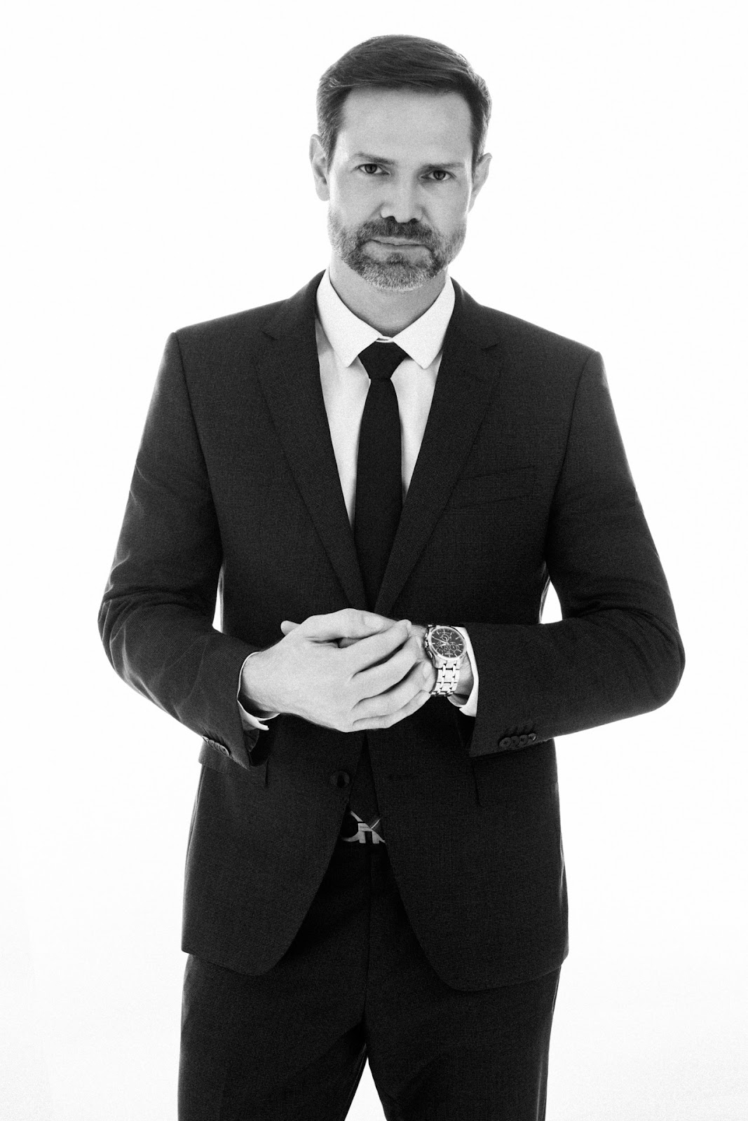 Felipe Benvenutti em retrato corporativo preto e branco com m�os ajustadas � frente do terno.