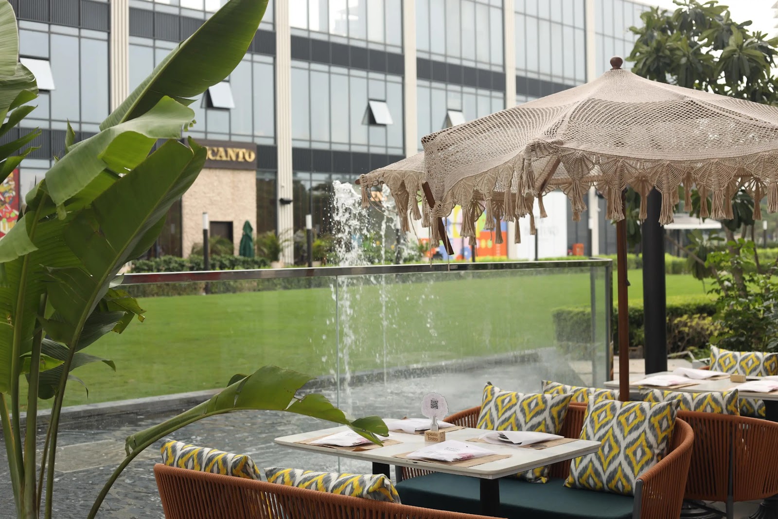 Spezia Bistro alfresco seating with macramé umbrella and fountain view at Magnum Global Park