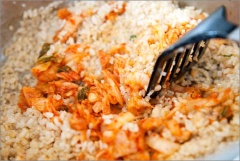 Đung nóng 2 muỗng canh dầu ăn, thêm cơm vào đảo trong vài phút hoặc cho đến khi cơm có màu vàng. Thêm kim chi cắt nhỏ, trứng, thịt bò và hành lá. Rang thêm 1 vài phút cho cơm ngấm đều thì tắt bếp.