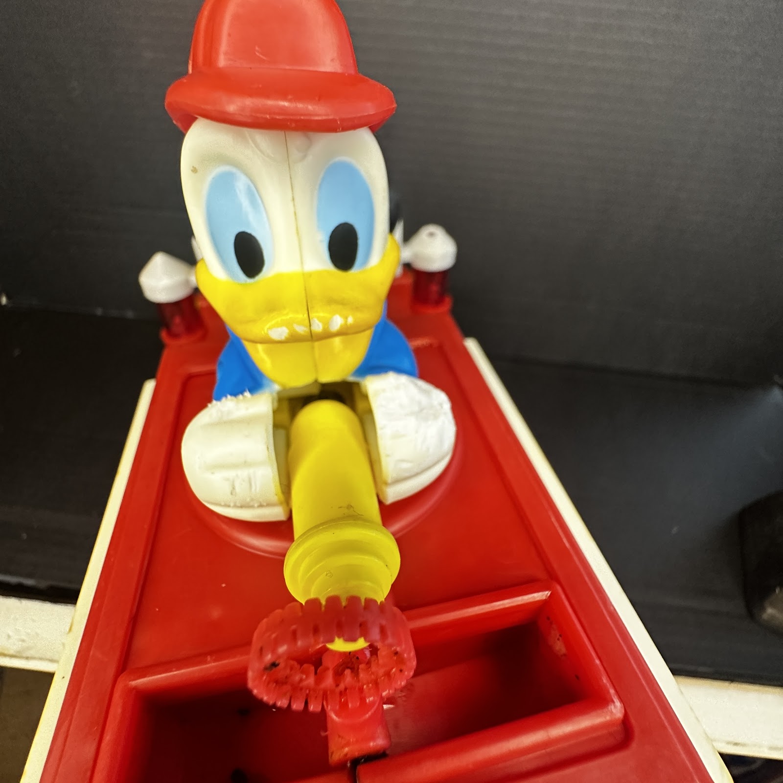 Vintage Illco Toy Co Donald Duck friction-powered fire truck, circa 1970s, showing heavy paint wear consistent with play use