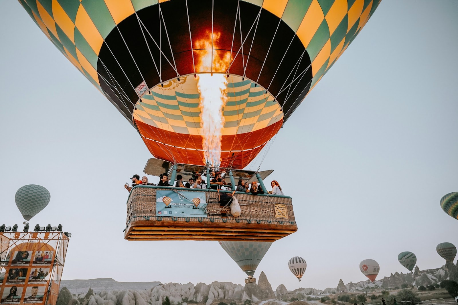 Travelers riding in a hot-air balloon above Cappadocia’s rocky valleys and fairy chimneys in Türkiye.
