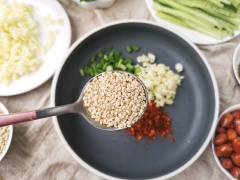 Làm hỗn hợp sốt trộn mì cay: cho vào chảo 1 muỗng canh ớt khô xay, 1 muỗng canh tỏi băm nhỏ, 1 muỗng canh hành lá, 1 muỗng canh mè trắng, 1/2 muỗng cà phê tiêu, 100-150ml dầu ô liu đun sôi, khuấy đều.