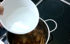 Tiếp theo, đổ nước dừa vào, đậy kín nắp, nấu sôi liu riu cho phần nước cạn gần hết. Lâu lâu dùng muỗng vớt bỏ bọt nổi trên mặt nồi.