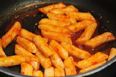 Khi hỗn hợp tương ớt đã sôi thì cho bánh gạo và chả cá thác lác vào và nêm 2 muỗng cà phê hạt nêm, 1 muỗng cà phê đường, 1/4 muỗng cà phê bột ngọt và 1/2 muỗng cà phê tiêu vào hỗn hợp tương ớt và bột gạo cho đến khi mọi thứ chín và nước đặc sệt lại thì tắt bếp.