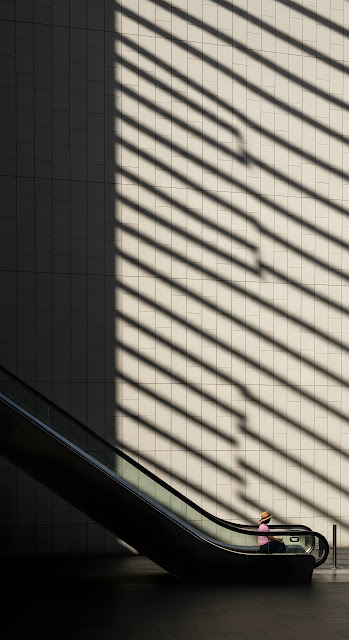 Minimalist Indoor Architecture Photo of Woman on Escalator with Sun Stripe Shadows - Free mobile Wallpaper