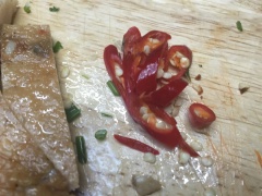 Chả cá đã được chiên sẵn, chỉ cần mang cắt miếng vừa ăn. Hành lá, ngò rí rửa sạch, cắt nhuyễn. Ớt cắt lát.