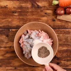 Phần nhân bánh: Cho 200gr thịt xay vào tô cùng với 150 tôm sú cắt nhỏ, ướp 1 muỗng canh nước mắm, 1/2 muỗng canh hạt nêm, 1/2 muỗng canh đường, 1 muỗng cà phê tiêu xay, trộn đều.