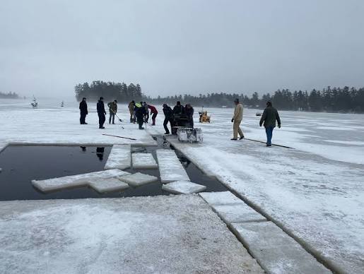 People on the frozen lake around cut ice blocks