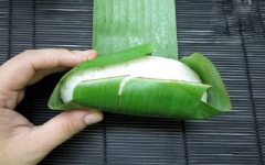 Bao kín quả chuối. Quấn lá chuối xung quanh. Làm lần lượt cho hết chuối và xôi.