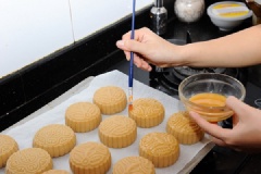 Mở trước lò nướng ở 200 độ C. Xếp bánh trung thu nhân bí đỏ hạt dưa lên khay nướng rồi đặt vào lò nướng. Sau 7-10 phút lấy bánh ra rồi đặt lại lò nướng tiếp. Lặp lại thêm 3 lần nữa. Ở lần lấy bánh ra thứ 3 và thứ 4 thì nhớ phết thêm hỗn hợp lòng đỏ lên mặt bánh trung thu nhé.
