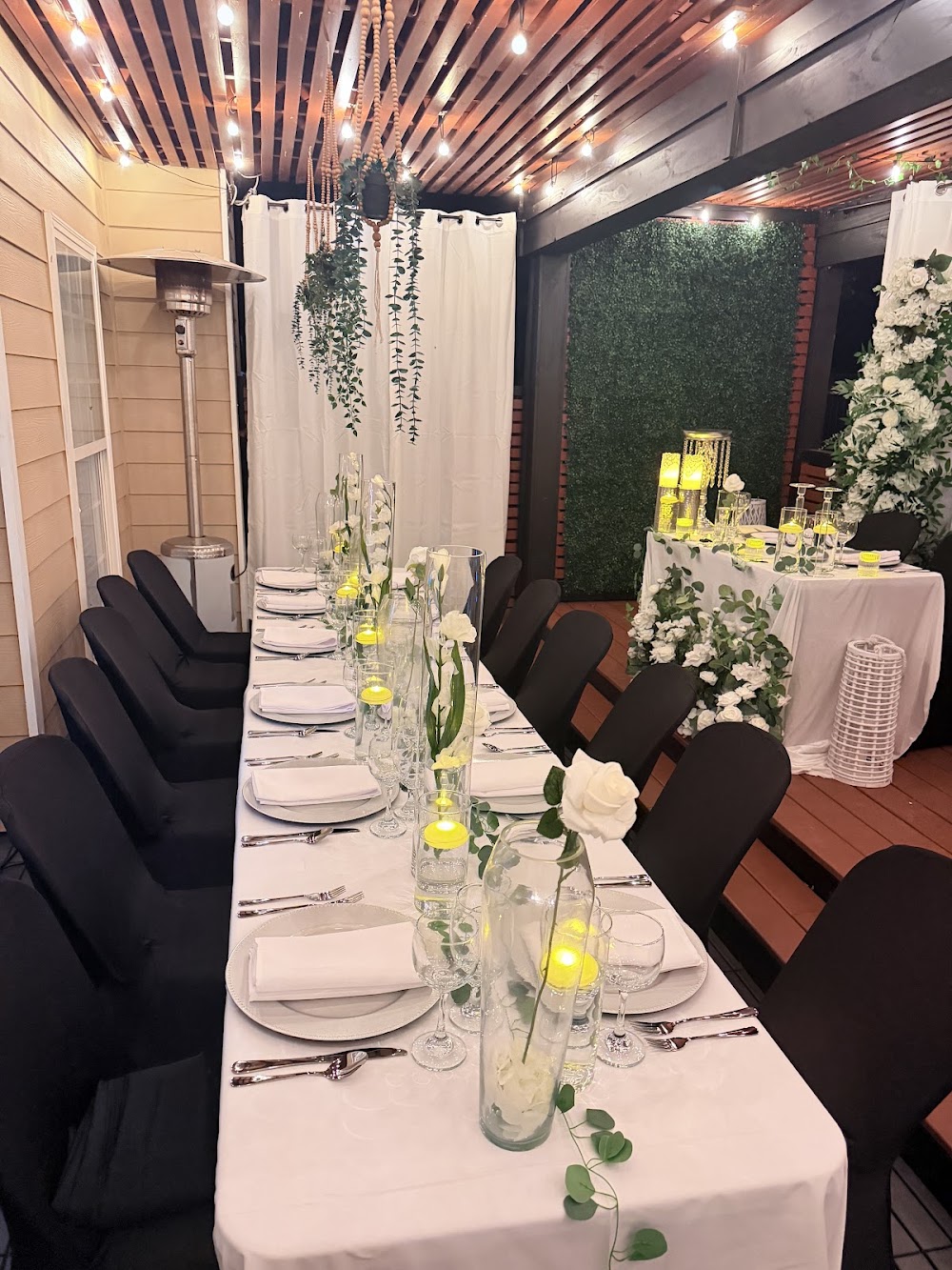 White-linen wedding reception table under string lights on the patio