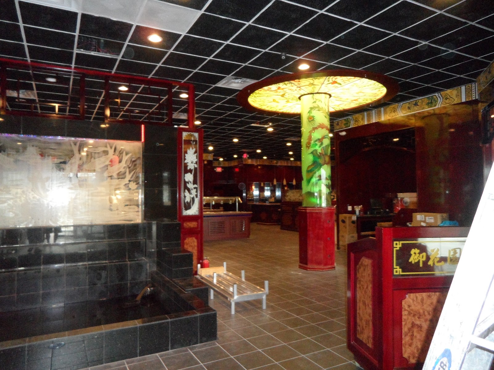 Interior view featuring a black tiled structure, a decorative green column, and a red counter with gold Chinese characters.
