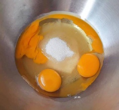 Tiếp theo cho 3 quả trứng vào âu khác cùng chút muối, 100g đường. Bạn dùng máy đánh trứng, đánh trứng ở mức nhỏ rồi tăng dần đến khi trứng bông mịn, đường tan hoàn toàn thì ngưng. Sau đó, đổ hỗn hợp sữa bơ khi nãy vào cùng tinh chất vani. Dùng phới lồng trộn lên cho thật đều.