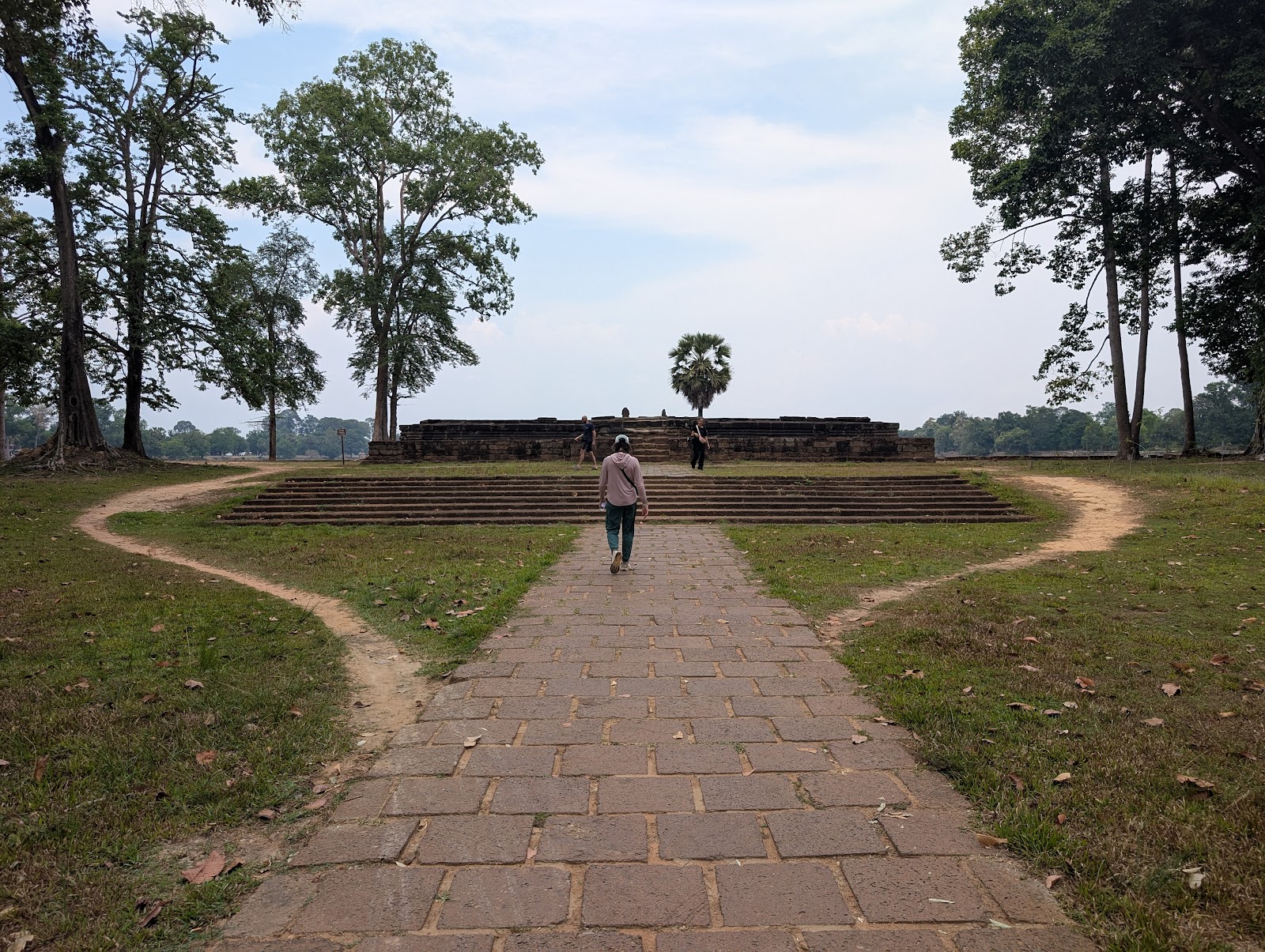 A stone path leading to a platform with eight steps up,
                 however a dirst desire path is formed in the grass on each
                 side of the stairs where people walked up the grass hill to
                 avoid the stairs