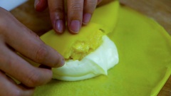 Gói bánh crepe sầu riêng: trải một lớp bánh crepe ra mặt phẳng, múc một lượng vừa đủ kem tươi whipping vào giữa, thêm sầu riêng lên trên rồi gói crepe lại thành chiếc bánh vuông vức và căng phồng. Làm lần lượt cho đến hết. Cho bánh crepe sầu riêng vào tủ lạnh rồi thưởng thức sẽ ngon hơn.