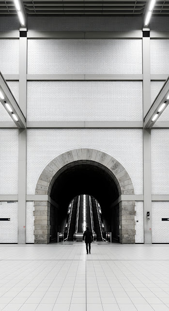 Symmetrical View of a Person Walking Under a Stone Archway in a Modern Underground Station - Free mobile Wallpaper