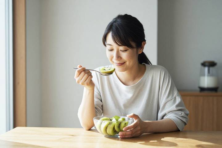 朝食に新鮮なキウイを楽しむ女性