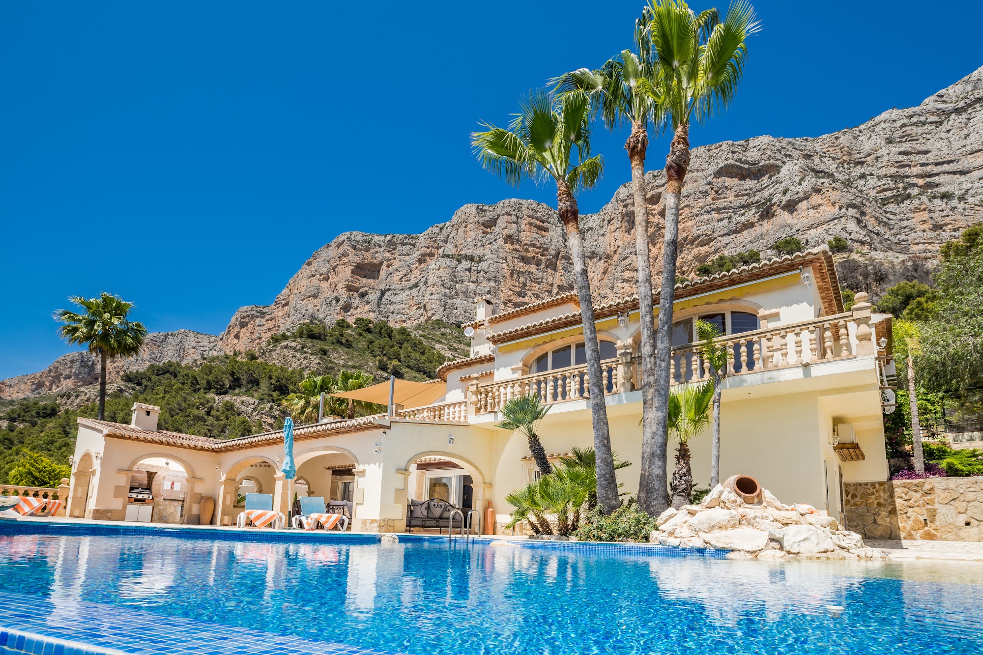 Villa exterior with palm trees and mountain backdrop