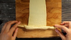 Cách làm bánh mì cua (cách tạo hình) đẹp mắt: Díu các mép bột làm bánh mì cua phô mai lại để có phần bột hình viên tròn với mặt bột căng, sau đó vo dài viên bột khoảng 30cm với một đầu to và đầu còn lại nhỏ hơn. Dùng cây cán bột cán mỏng bột bánh mì sau đó tạo hình 2 càng cua, cho miếng phô mai ở giữa và bắt đầu cuộn lại để tạo thành hình con cua hoàn chỉnh. Không nên cán quá mỏng vì bánh mì cua nhân phô mai sau khi nướng sẽ dễ bị mất các dấu vân.