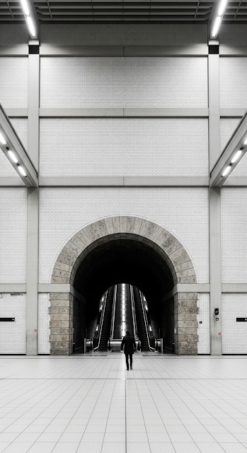 Symmetrical View of a Person Walking Under a Stone Archway in a Modern Underground Station - Free mobile Wallpaper