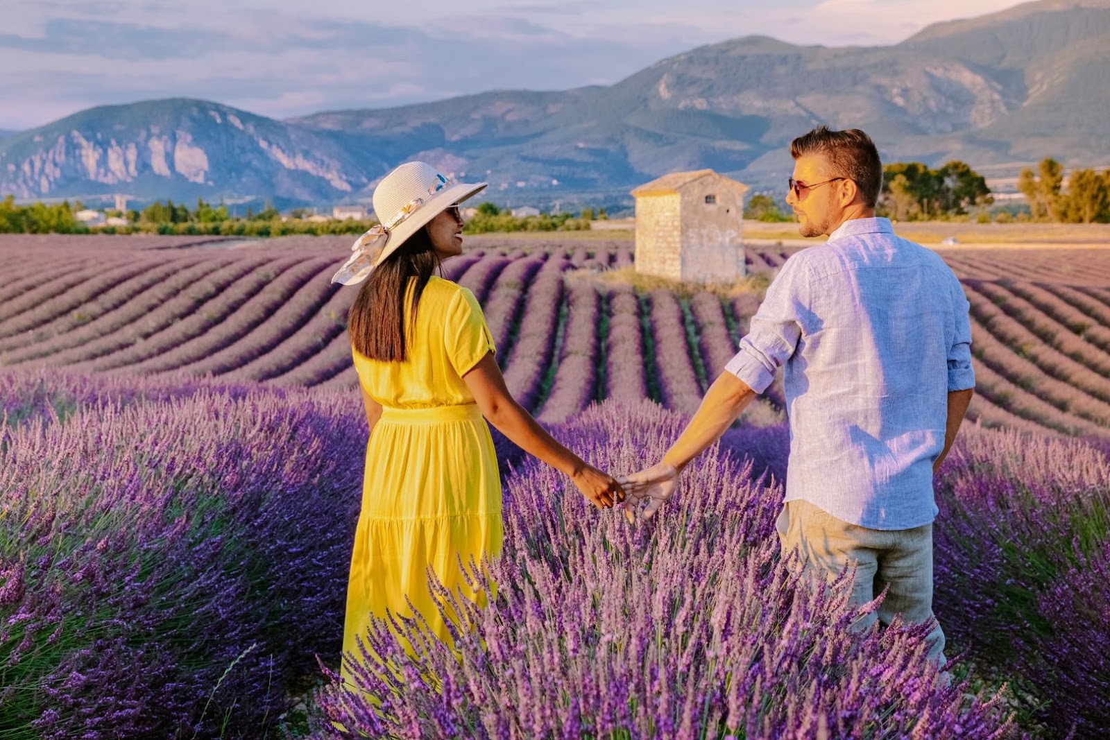 Couple walking together through rows of blooming lavender in Provence, France.