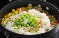 Tiếp đến cho cơm, thơm, hành lá và đổ hỗn hợp nước sốt ở trên vào. Đảo liên tục trong vòng 2 phút.
