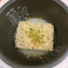 Gạo vo sạch, cho vào nồi cơm điện, chế nước vừa đủ theo mức gạo. Sau đó cho mì ramen vào kèm theo các gói gia vị, rau của mì. Bật nút nấu và chờ cơm cùng mì chín. Khi cơm đã chín, mở nắp ra, xới trộn lên là có thể thưởng thức nha.