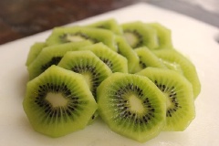Kiwi gọt vỏ, nho cắt đôi, bỏ hạt, dâu tây rửa sạch, cắt lát mỏng như hình bên. Chờ cho bánh được nướng chín thì thêm topping lên bánh.