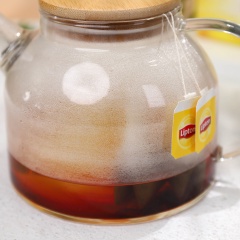 Đầu tiên, cho 2 gói trà túi lọc Lipton vào bình trà, rồi đổ 250ml nước sôi vào, đậy nắp lại, ủ trong vòng 5 phút thì lấy túi trà ra.