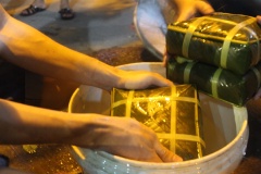 Bánh chưng nấu chín, vớt ra khỏi nồi, rửa sạch bánh chưng với nước lạnh. Đặt 2 cái bánh chưng lên nhau, sử dụng miếng ván gỗ nặng đặt lên bánh. Với cách làm này, phần nếp của bánh chưng xanh sẽ được săn chắc, không bị nhão.