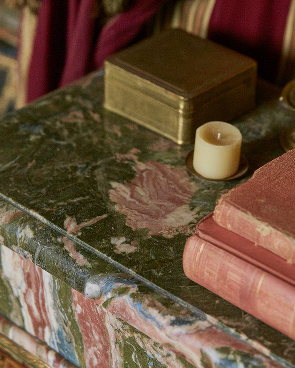 Richly veined green marble table with aged brass, candle and old books