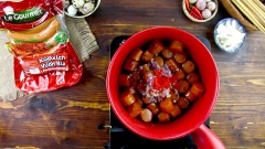 Thêm xúc xích vào nồi nước màu cùng với 20gr tỏi băm, 20gr hành tím băm, 10gr ớt băm, 30gr đường, 30ml nước mắm, 10gr hạt nêm, 5gr muối và 3gr tiêu. Trộn đều cho gia vị thấm vào xúc xích.