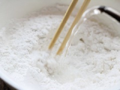 Trong 1 tô lớn, trộn bột mì, bột năng, muối, dầu ăn với nhau. Sau đó từ từ đổ 190 ml nước sôi vào. Dùng đũa đảo đều hỗn hợp bột.