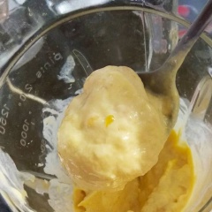 Khi xoài đã đóng băng cứng, bỏ sữa chua + xoài + mật ong + vani vào máy và xay nhuyễn (nếu xoài bị dính thành cục thì vẫn có thể dùng dao cắt nhé). Sẽ hơi khó xay vì xoài đã cứng thành đá, nên lúc xay, bỏ sữa chua xuống trước, cứ xay rồi tắt đi, đảo đều lên rồi xay tiếp. Liên tục xay + đảo đến khi đạt được một hỗn hợp mịn màng.