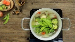 Khi nước xương đã trong ta vớt xương ra và lần lượt thả các loại rau củ vào. Để món canh bóng thả đa dạng và nhiều màu sắc, ta dùng 50gr cà rốt, 50gr súp lơ trắng, 50gr súp lơ xanh và 50gr đậu Hà Lan. Nêm nước dùng với nửa muỗng cà phê muối, 1 muỗng cà phê hạt nêm,1 muỗng cà phê đường và 1 muỗng cà phê nước mắm. Tiến hành thả bóng cuộn đã cắt và mọc son vào nấu chín. Sau đó vớt hết các loại rau củ, bóng bì, mọc son ra bát trước, tránh để trong nồi nước nóng lâu sẽ bị chín quá. Khi nào ăn mới đổ nước dùng vào.