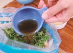 Ngò rí cắt nhỏ, cho vào túi cánh gà cùng 1 muỗng canh nước mắm, 1 muỗng canh nước tương, 30ml mật ong, 1 muỗng cà phê tỏi băm, 1 muỗng canh dầu mè vào, trộn đều.