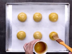 Để lò nóng 200 độ trong 15 phút. Chia nhân lava thành từng viên khoảng 8gr, nhân trứng sữa khoảng 15gr. Cho nhân lava vào bên trong nhân trứng sữa, bọc kín nhân. Sau đó, dùng vỏ bột bánh bọc bên ngoài, túm chặt bột ở phía đáy bánh. Cho bánh lên khay đã lót giấy, pha hỗn hợp phết bánh, dùng cọ phết lên mặt bánh trung thu Đài Loan, sau đó rắt ít mè đen. Đem bánh nướng ở nhiệt độ 200 độ trong khoảng 20 phút.