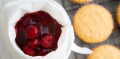 Cho mứt trái cherry vào túi bóp kem. Rạch bỏ phần giữa bánh. Bóp nhẹ mứt trái cherry xuống bánh.