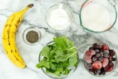 Cải xoăn rửa sạch, để ráo. Chuối lột vỏ, cắt miếng. Cho cải xoăn, chuối, việt quất và dâu đông lạnh vào máy sinh tố, thêm 1 muỗng hạt chia, 65g sữa chua (Greek Yogurt), 310ml sữa hạnh nhân. Bật mát xay thật nhuyễn mịn hỗn hợp, nếu thích lạnh hơn bạn có thể cho thêm đá vào xay cùng nha.