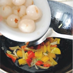 Tiếp theo, cho lần lượt vải, gà viên, hành lá cùng gia vị 1/2 muỗng cà phê tiêu, 1 muỗng canh nước mắm, 1 muỗng cà phê hạt nêm vào, đảo đều thêm 5 phút.